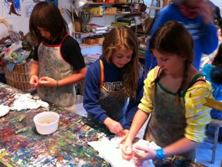 Preparing shirts for tie-dye Three girls wrap rubber bands around white t-shirts