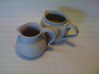 Two unfired ceramic pitchers with handles